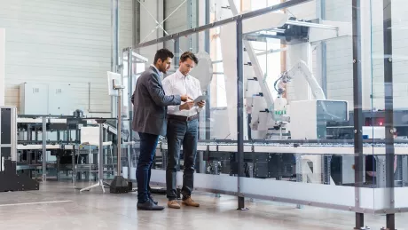 Business man with tablet in front of industry 4.0 machine