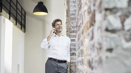 Mann steht mit Smartphone telefonierend im Büro