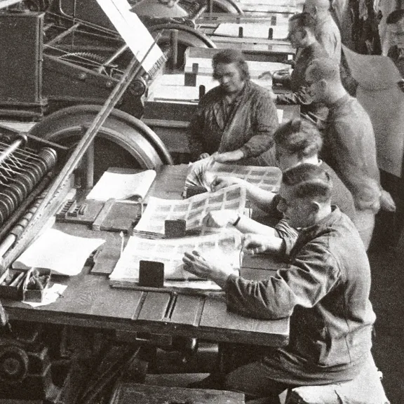 Historische Aufnahme von Mitarbeitende an einer Maschine