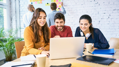 Three people sitting in front of a computer during a meeting