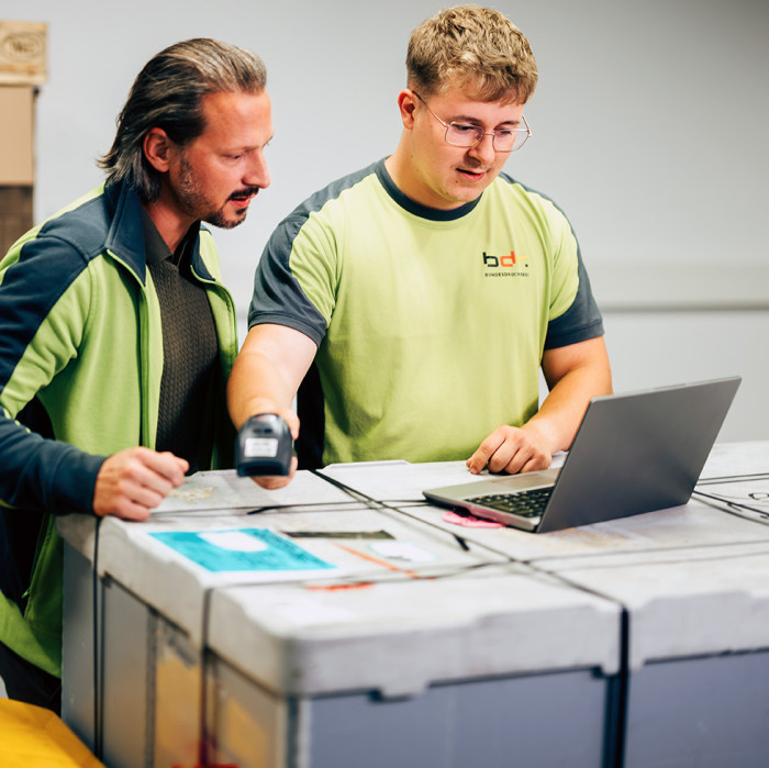 Zwei Personen stehen vor einem Computer und schauen sich etwas an.