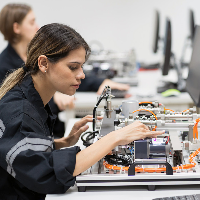 Frau sitzt am Schreibtisch und arbeitet mit einer Elektronikplatte.