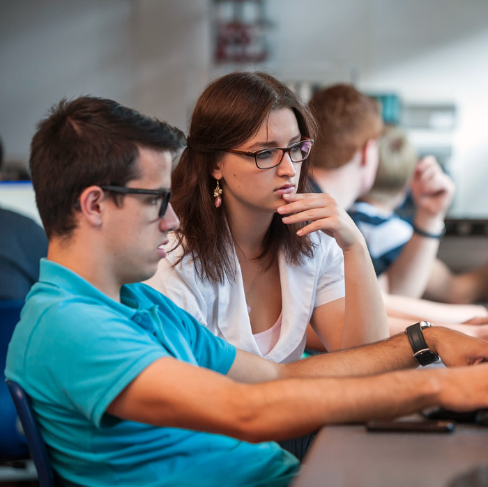 View of two people sitting in front of a computer.