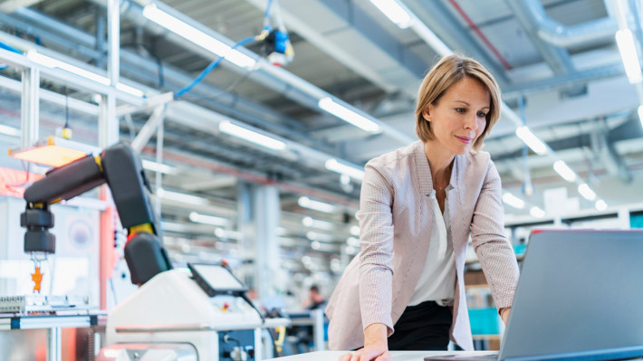 Woman standing at laptop in industrial hall